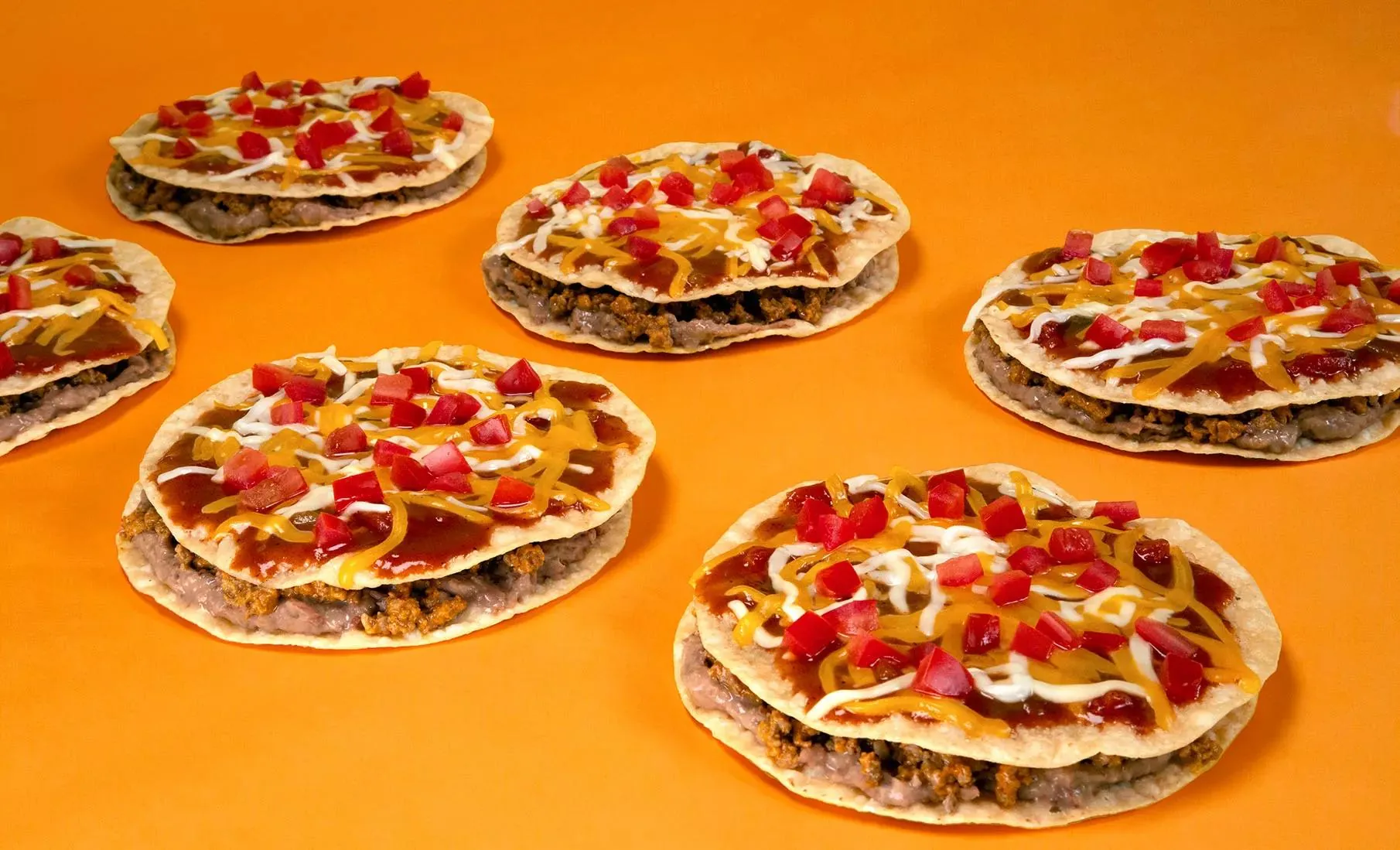 Taco Bell Mexican Pizza with two tortilla layers, seasoned beef, refried beans, cheese, tomatoes, and no visible lettuce